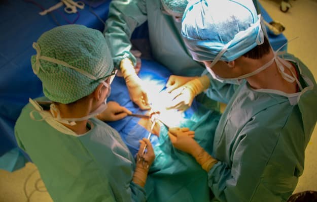 Equipe médica realizando cirurgia de transplante em centro cirúrgico, vista de cima.