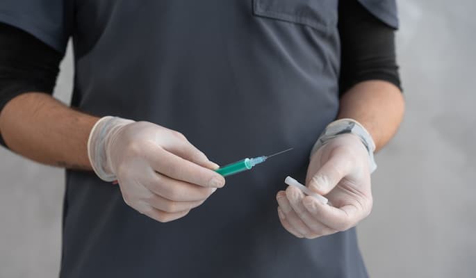 Profissional de saúde preparando uma seringa com medicamento Benzetacil para aplicação.