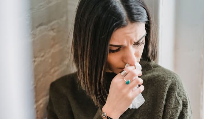 Mulher segurando lenço com sintomas respiratórios e alergia tratada com hidroxizina.