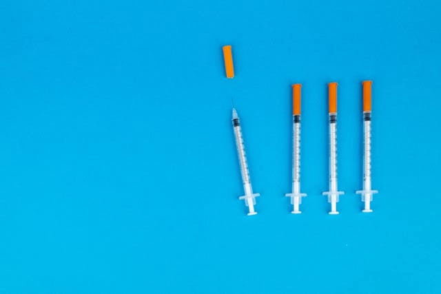 Seringas sobre fundo azul, representando o alerta sobre caneta emagrecedora contrabandeada e os riscos do uso de medicamentos injetáveis sem procedência.